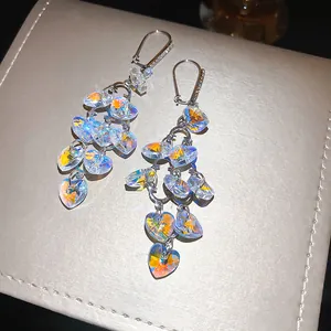 Close-up of heart-shaped crystal tassel earrings with sparkling iridescent finish.