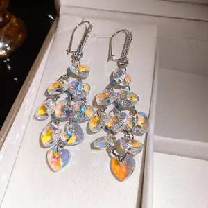 Macro detail of iridescent glass heart tassel earrings with sparkling cubic zirconias.