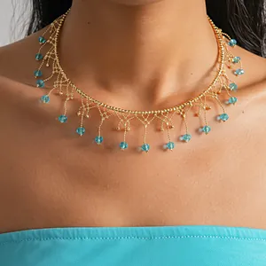Elegante collana girocollo dorata con frange di cristallo azzurro indossata su un modello