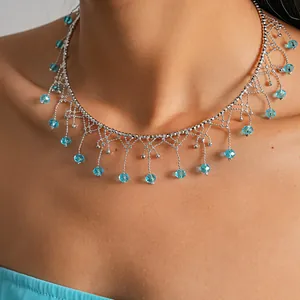 Primo piano di un'elegante collana girocollo in argento con frange di cristallo blu e pizzo.