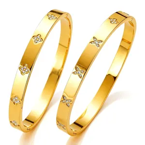 Macro-detail van gepolijste vergulde titaniumstalen armbanden met diamanten klaverontwerp.