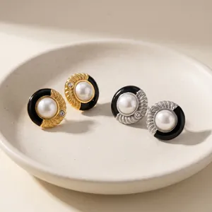 Détail macro d'élégantes boucles d'oreilles en acier avec émail noir et perles