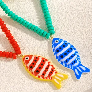 Gros plan de deux pendentifs poissons tropicaux colorés sur des colliers en perles