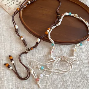 Detailed view of bohemian beaded waist chains in brown and off-white cords