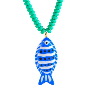 Vue détaillée d'un pendentif poisson à rayures bleues et blanches avec des perles vertes