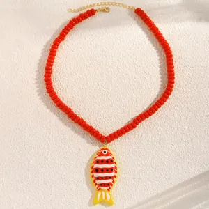 Détail du pendentif poisson tropical avec des perles rouges et des motifs rayés