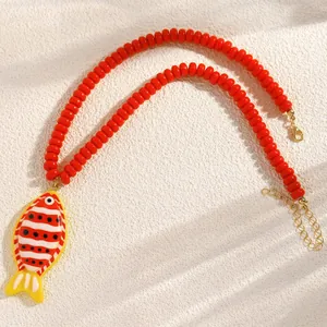 Gros plan détaillé d'un collier de perles rouges avec un pendentif poisson tropical
