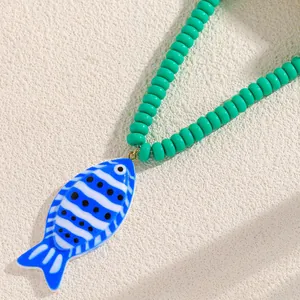 Vue détaillée d'un pendentif poisson tropical de style océan sur un collier perles vertes