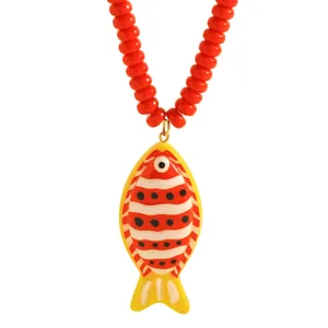 Gros plan détaillé d'un pendentif poisson tropical sur une chaîne de perles rouges
