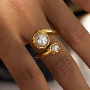 Dettaglio di un anello in acciaio inossidabile dorato con due eleganti perle bianche