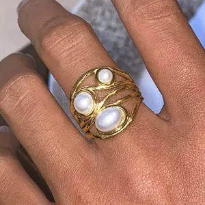 Dettaglio di un anello multifilo in acciaio inossidabile con tre perle sintetiche.