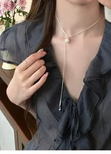 Close-up of a delicate silver popcorn pendant Y-necklace worn with a ruffled dress.