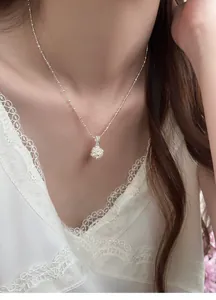 Detailed close-up view of an elegant popcorn pendant necklace with pearls on a model neck.