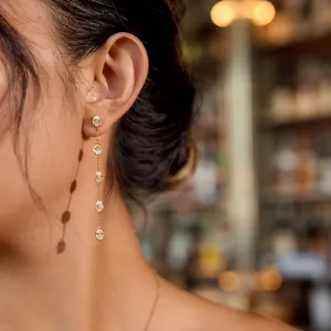 Close-up of gold stainless steel long tassel earrings with oval zircons on ear.