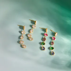 Macro detail of multicolor and clear zircon stone drop earrings on a blue textured background