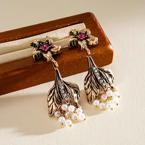Vista dettagliata di orecchini vintage a fiore con perle e strass su supporto in legno.