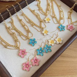 Detailed view of sweet enamel flower jewelry set including gold necklaces and earrings