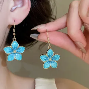 Close-up of sweet blue oil-drop flower drop earrings with golden accents for summer.
