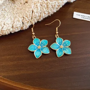 Detail of blue enamel five-petal flower drop earrings with golden fishhook wires