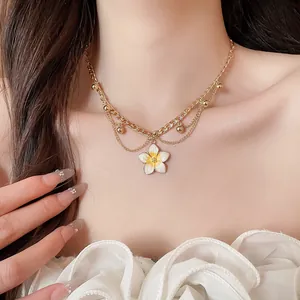 Close-up of a sweet enamel flower pendant necklace on a model for summer vacation style