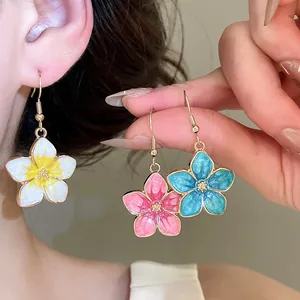 Close-up of sweet enamel flower drop earrings in white, pink, and blue colors.
