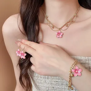 Detailed view of pink enamel flower jewelry set with gold necklace and bracelet