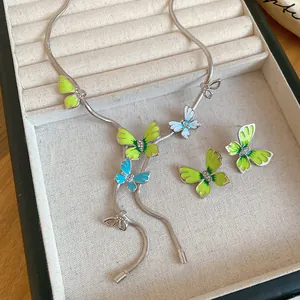 Detail view of forest-style green and blue enamel butterfly necklace and earring jewelry set.