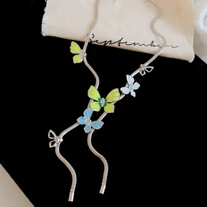 Macro view of silver snake chain necklace with green and blue enamel butterfly pendants