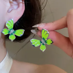 Close-up of lime green butterfly earrings with enamel finish and small rhinestones