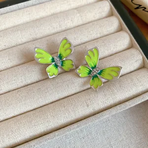 Detail view of green enamel butterfly stud earrings with rhinestones in jewelry box.