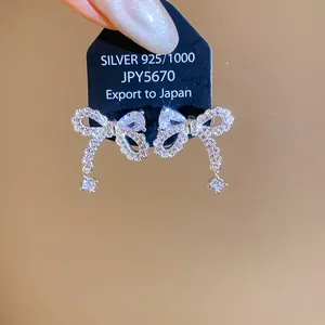 Detailed macro view of silver bow stud earrings with sparkling cubic zirconia stones