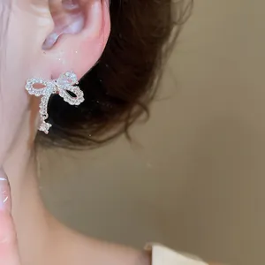 Elegant silver zircon bow-knot earrings with a teardrop stone on model's ear