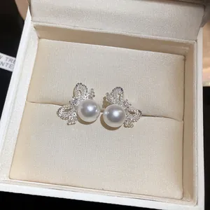 Detailed view of elegant silver bow earrings with round white pearls in a jewelry gift box.