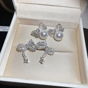 Elegant silver bow stud earrings with sparkling zircons and white pearls in a jewelry box