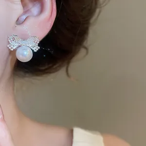 Close-up detail of silver zircon bow knot stud earrings featuring a lustrous white pearl.
