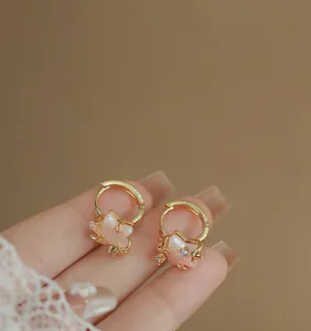 Close-up of gold star earrings with zircon accents and a feminine lace background.