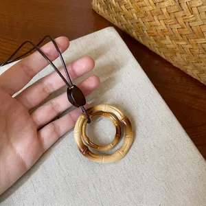 Macro detail of resin bamboo-style double ring pendant necklace on canvas background.