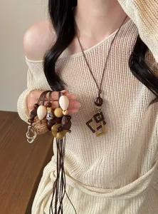 Close-up of minimalist geometric resin pendants in warm earthy tones held by a model