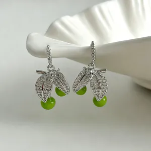 Close-up of elegant leaf-shaped earrings with sparkling zircons and green cherry beads