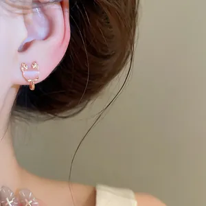Close-up shot of a sweet pink oval cat's eye stone ear clip on a model's ear, detail view