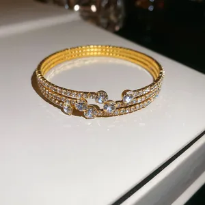 Détail d'un élégant bracelet jonc plaqué or avec trois rangées de zircons étincelants