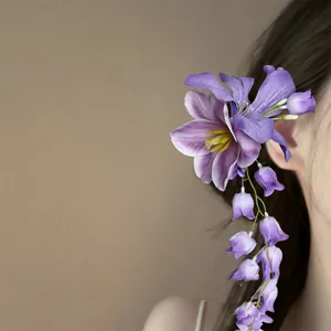 Elegante paarse stoffen bloemen haarspeld met hangende knoppen op een model, prachtig.