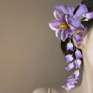 Gedetailleerd zijaanzicht van een elegante paarse stoffen bloem haarclip met kwastje