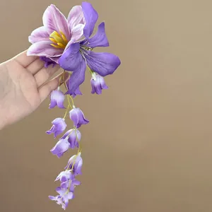 Close-up van elegante paarse stoffen bloemenhaarclip met lange, trapsgewijze bloemenkwast