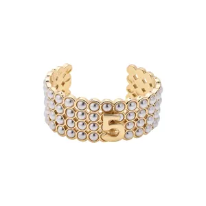 Elegante bracciale rigido dorato multistrato con perle e motivo vintage numero cinque
