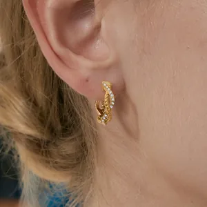 Elegant gold twisted stainless steel hoop earrings with sparkling crystals worn on ear