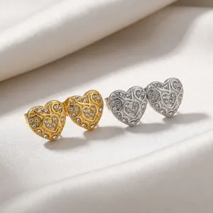 Close-up detail of heart-shaped stud earrings in gold and silver with sparkling crystals