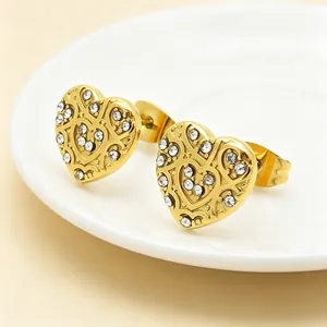Close-up of 18K gold plated heart earrings with intricate filigree and rhinestones.