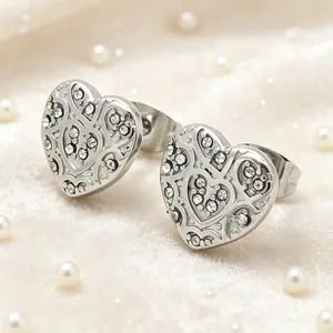 Detail view of silver heart-shaped filigree earrings with sparkling rhinestone accents.