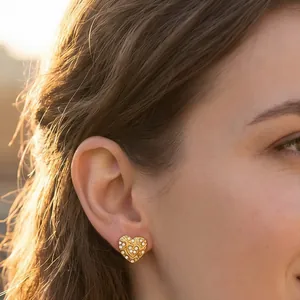 Detail view of a vintage 18K gold plated heart stud earring with crystal inlay on model